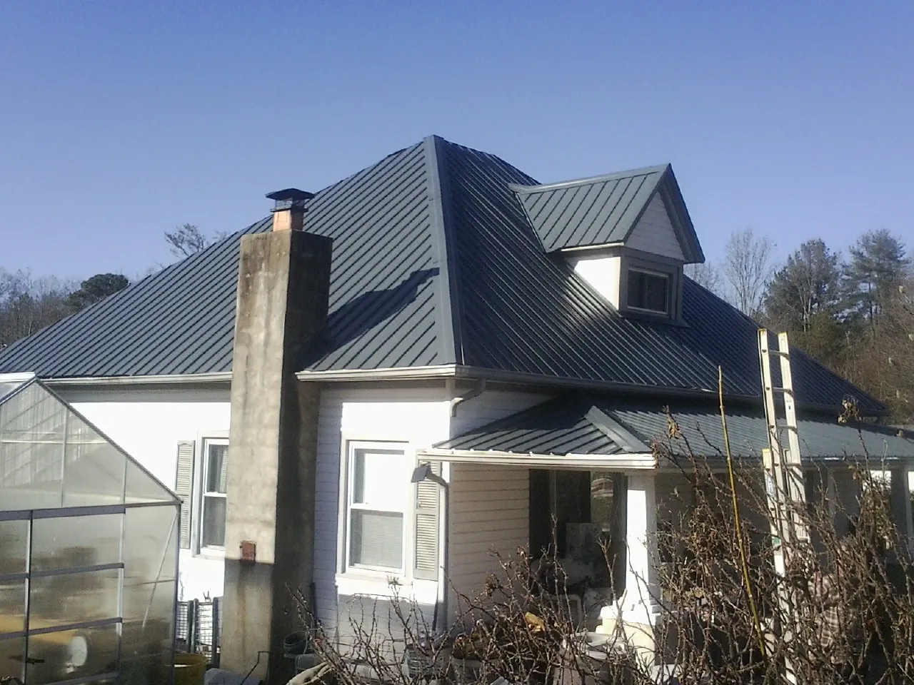 Dark blue standing seam metal roof on a white farmhouse with dormer — Slate & Tile Roof Repair by Roofing Brothers in Melcroft