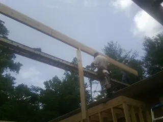 Carpenter setting a ridge beam over a new addition frame — Ice Dam Removal by Roofing Brothers in Melcroft