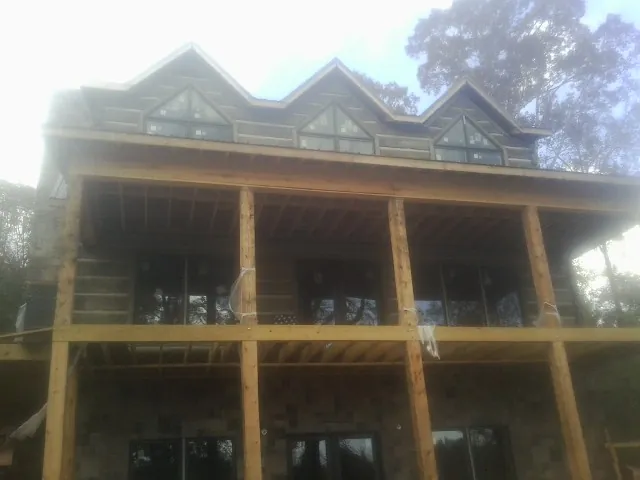 Dormers and porch framing on a large log home under construction — Roof Coating work by our crew in Melcroft