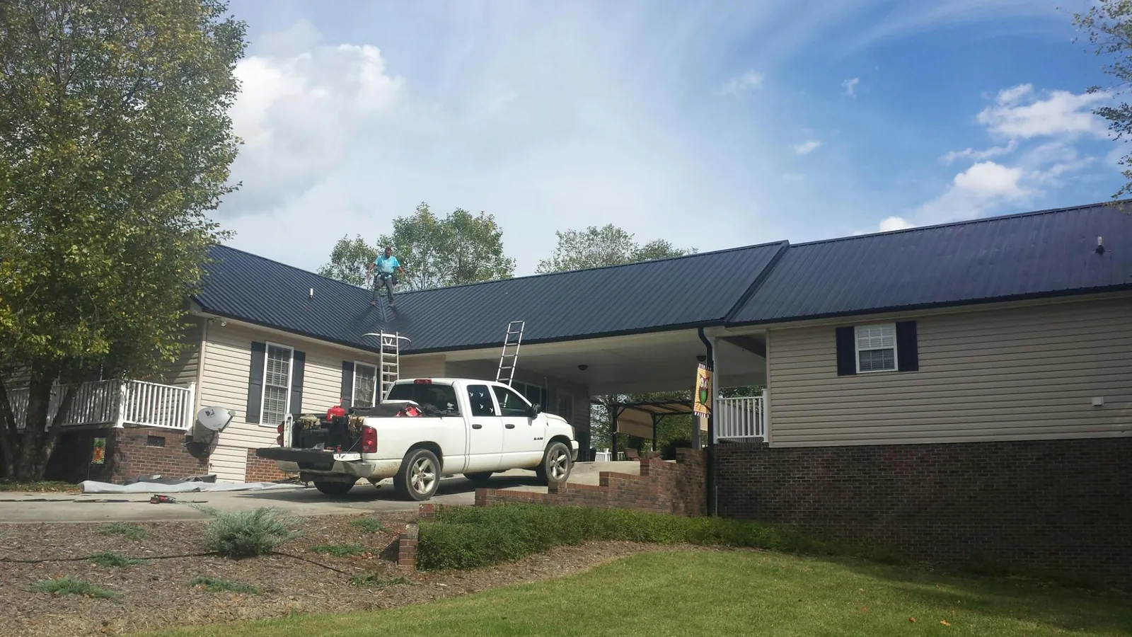 Black metal roof over a home and attached breezeway with ladders set in Melcroft