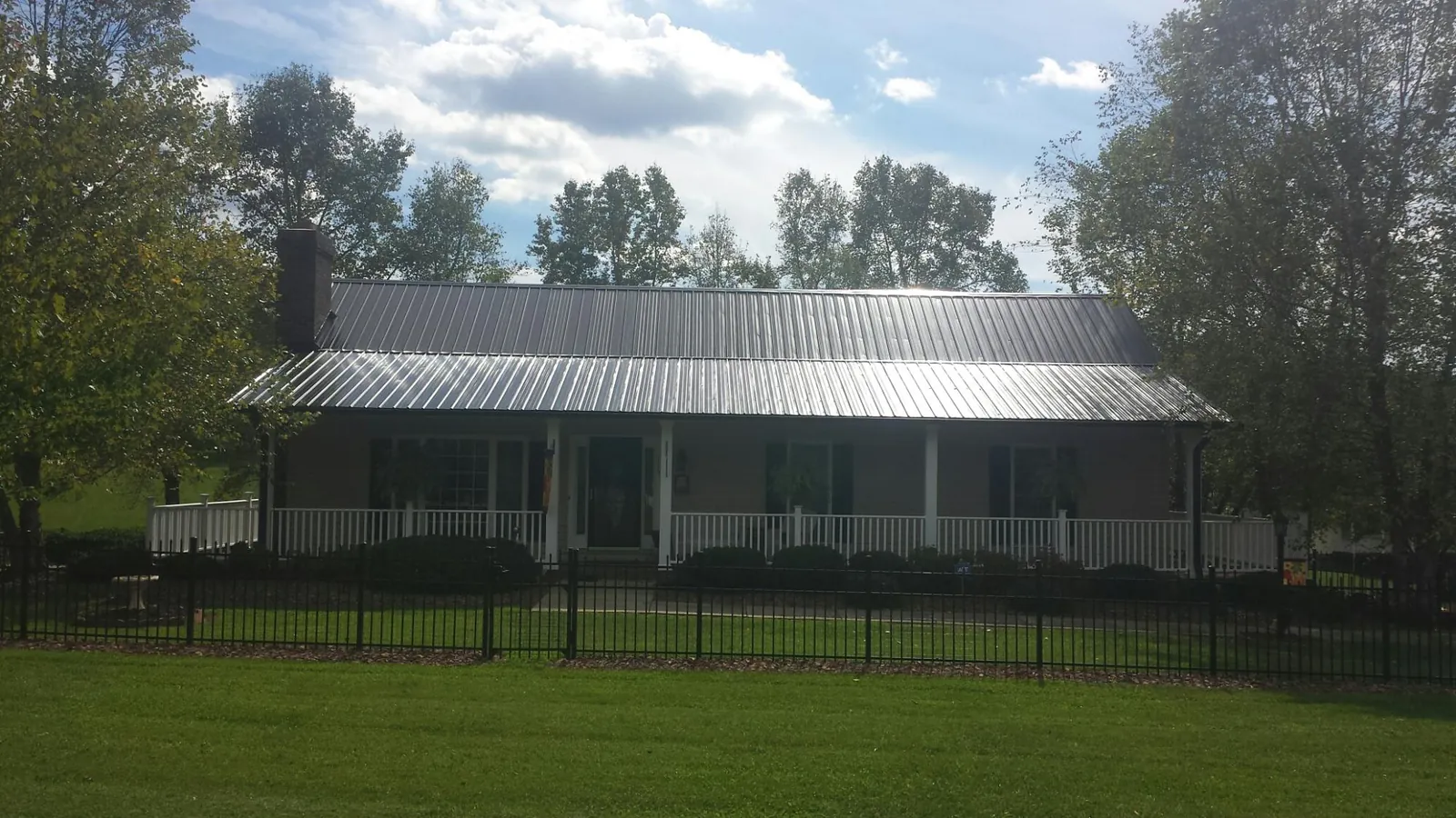 Gray metal roof on a brick ranch with a full width front porch — Gutter Guard Installation work by our crew in Melcroft