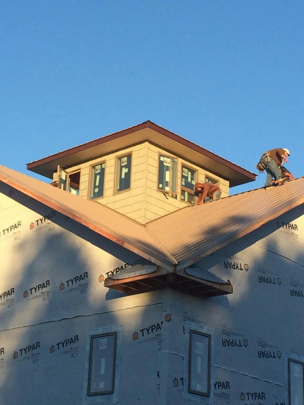Roofers working around a rooftop cupola on a new metal roof at sunset — Roof Waterproofing in Melcroft by Roofing Brothers